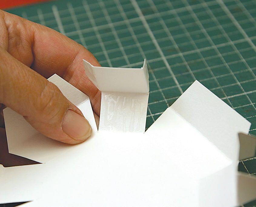 Beyaz karton kutunun kanatları parmakla yukarı katlanarak kenarlar kaldırılıyor