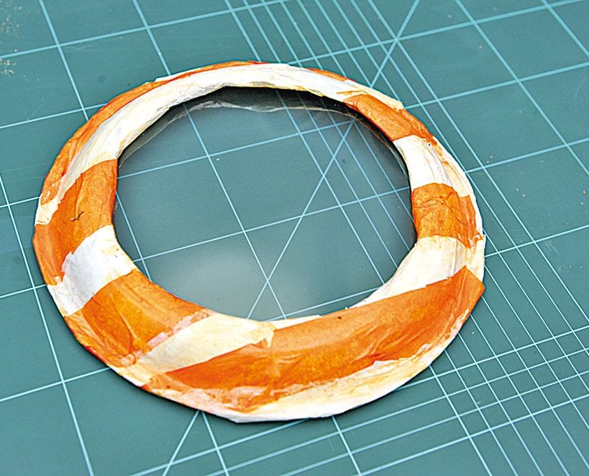 Turuncu ve beyaz kağıt şeritlerle sarılarak can simidine benzetilmiş tabak halkası