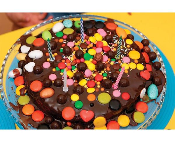 Çikolatalı doğum günü pastası: üzeri renkli şekerleme drajeler ve mumlarla süslenmiş çikolata kaplı pasta
