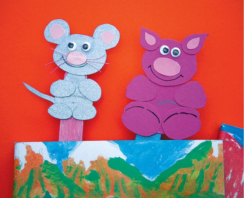 Mavi fare ve pembe domuz kitap ayraçları, renkli boyanmış bir sayfanın arkasından çıkıyor