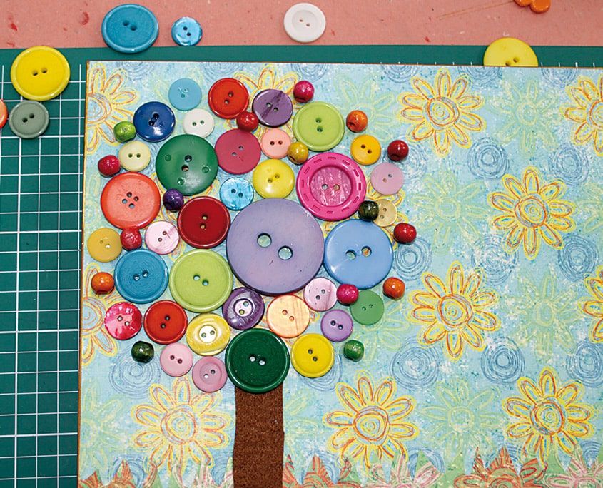 Farklı boy ve renkte düğmelerle tamamen doldurulmuş yuvarlak ağaç tacı, desenli pano üzerinde