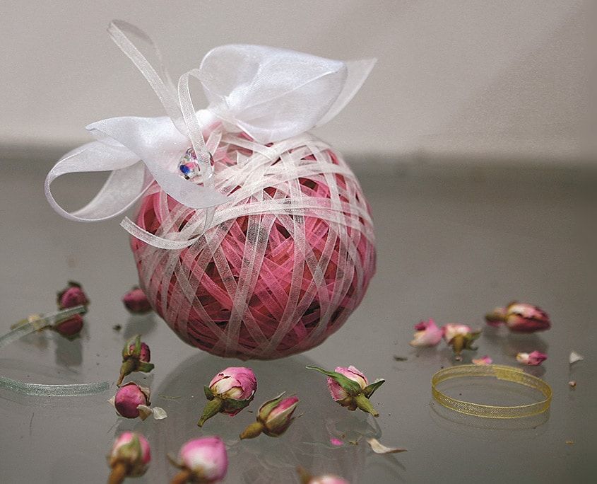 Pembe kurdele koku topu beyaz organze fiyonkla, çevresine kurutulmuş gül goncaları dağılmış