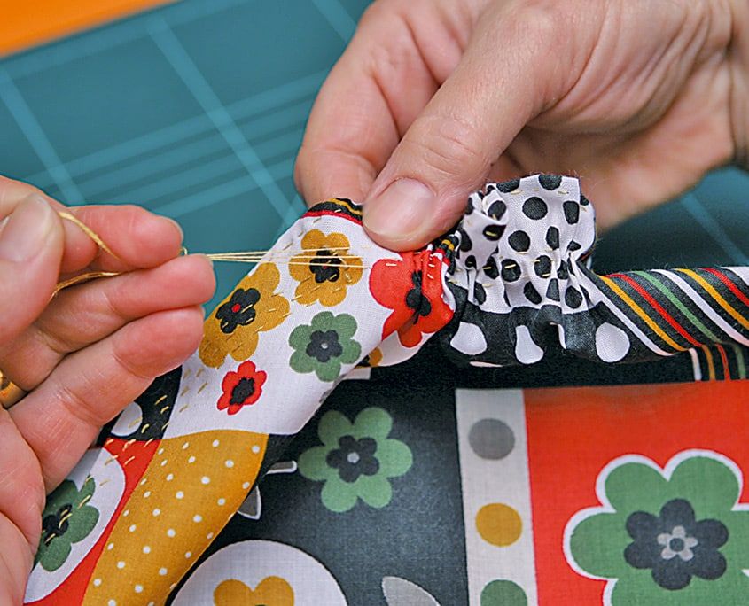 Teyel ipliği çekilerek yuvarlak desenli kumaşın kenarı kese gibi büzülüyor