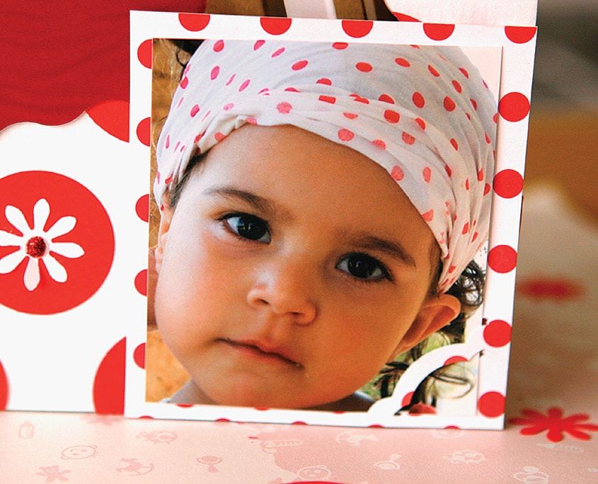 Tamamlanmış puantiyeli kart: başörtülü bir çocuğun fotoğrafı kırmızı benekli ve çiçekli çerçeve içinde