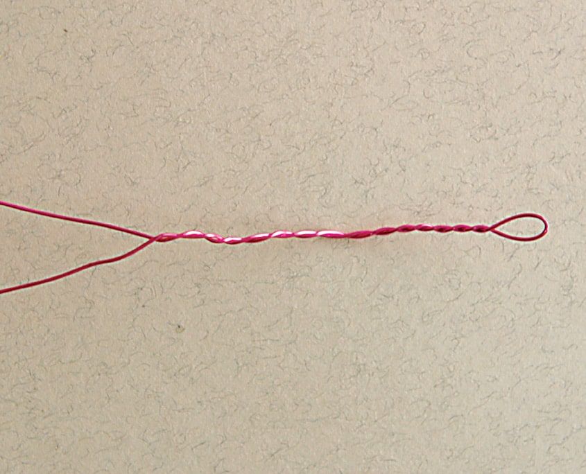 Ucu ilmek yapılıp kendi üstüne bükülmüş pembe tel, kağıt çiçeğin sapı olacak