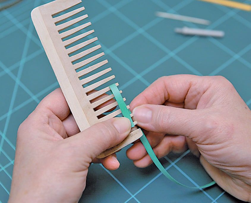 Yeşil quilling şeridinin ucu tahta tarağın dişlerinden birine dolanarak ilk ilmek atılıyor