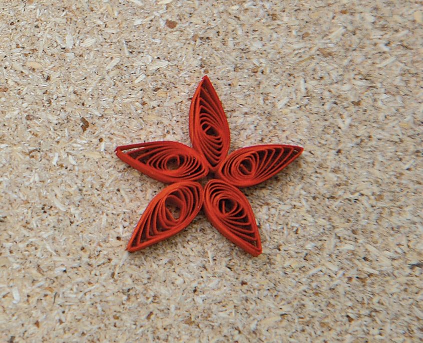 Beş damla şekilli kırmızı rulonun birleşmesiyle yapılmış quilling deniz yıldızı