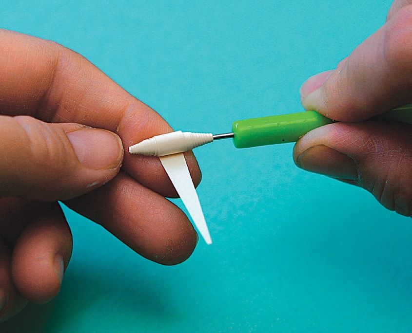 Sivri uçlu beyaz kağıt şerit quilling kalemine sarılarak konik kelebek gövdesi yapılıyor