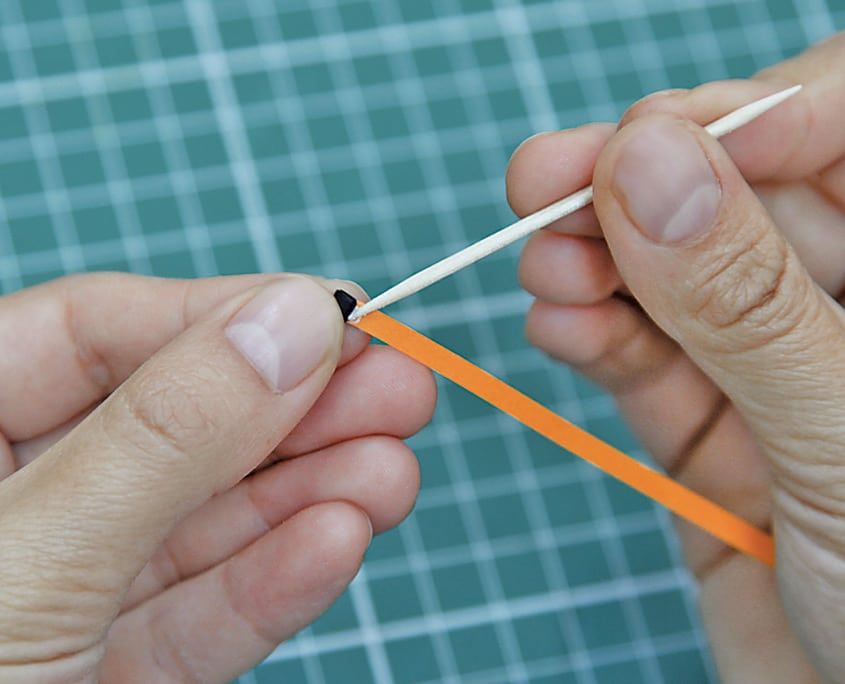 Turuncu quilling şeridinin ucu ince çubuğun yarığına takılıp sarılmaya başlanıyor