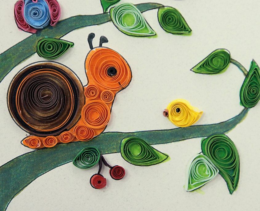 Ağaç dalındaki kahverengi ve turuncu sarmal kabuklu quilling salyangoz, çevresinde yeşil yapraklar