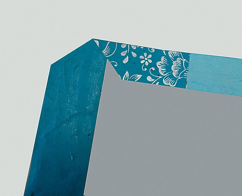 Desenli kağıdın köşesi kapağın içine çapraz katlanıyor, gri karton zemin üzerinde