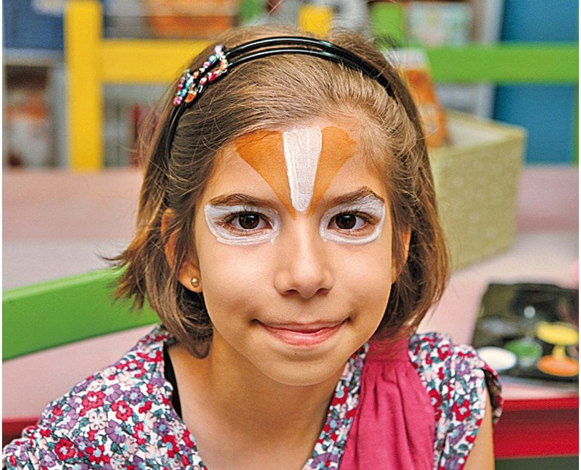 Göz çevresine beyaz boyayla kedi gözü biçimi çizilmiş, alında turuncu ve beyaz desen