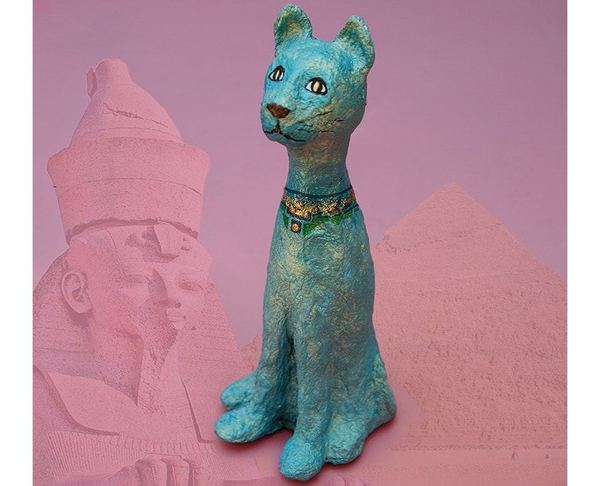 Firavunun kedisi: turkuaz boyalı kağıt hamuru kedi heykeli, arkada sfenks ve piramit görseli