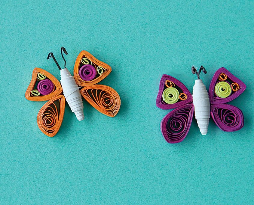 Beyaz konik gövdeli, siyah antenli turuncu ve mor iki quilling kelebek tamamlanmış