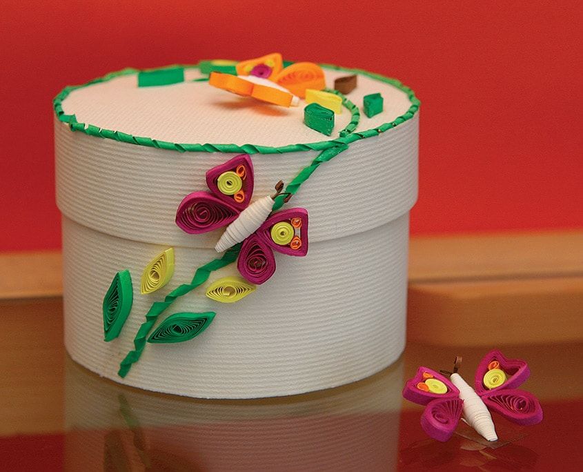 Quilling kutu süsleme: kapağı ve yanı kelebekler, yeşil dal ve yapraklarla süslenmiş yuvarlak kutu
