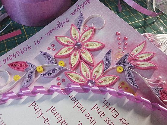 Mor ve pembe quilling çiçekler, boncuklar ve kıvrık kurdeleyle süslenmiş kartın köşesi yakın plan