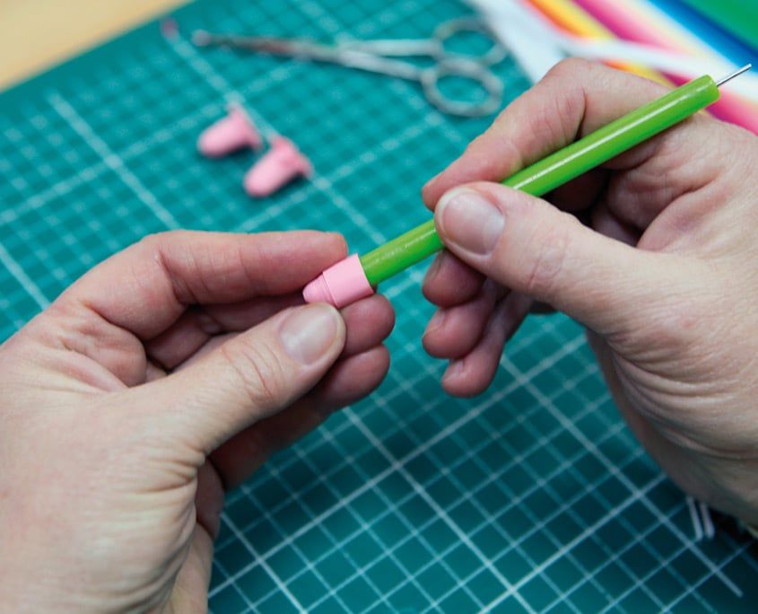 Pembe şerit yeşil saplı quilling kalemine sıkıca sarılarak kalın bir rulo yapılıyor