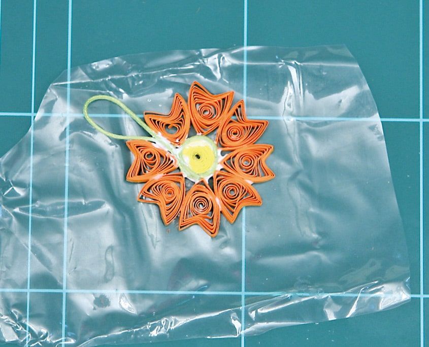 Turuncu quilling çiçek kolyenin yakın görünümü, göbek ve sivri yaprak halkaları naylon üstünde