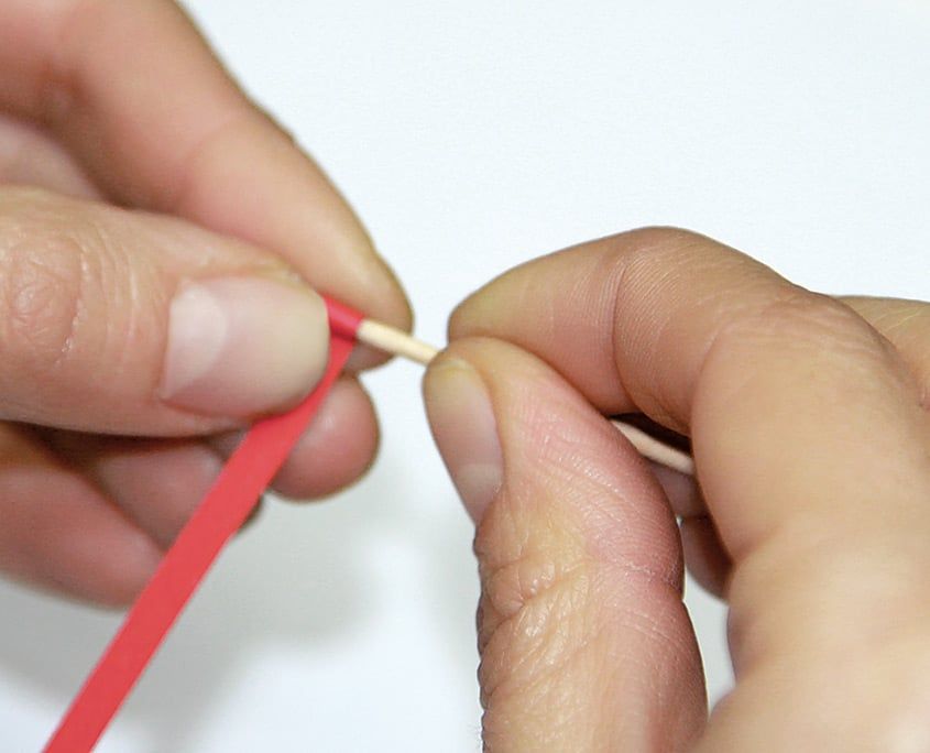 Kırmızı quilling şeridinin ucu kürdana takılıp parmaklarla sarılmaya başlanıyor