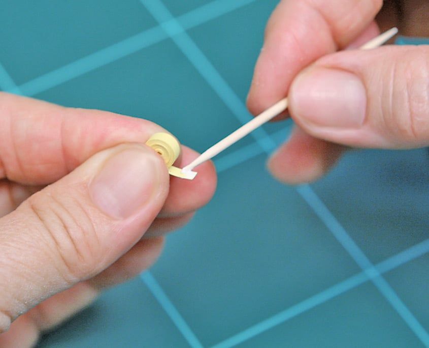 Yarıklı quilling çubuğuna sarı kağıt şeridin ucu takılıp parmaklarla sarılmaya başlanıyor