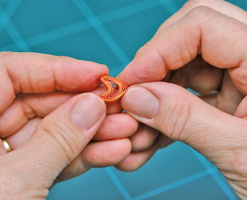Turuncu quilling damlasının ucu parmaklarla kıvrılarak sivri yaprak biçimi veriliyor