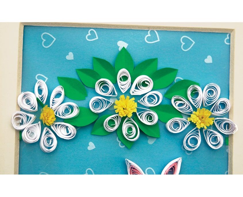 Kalpli mavi zemine yapıştırılmış üç beyaz quilling papatya ve yapraklar, altta tavşan kulakları görünüyor