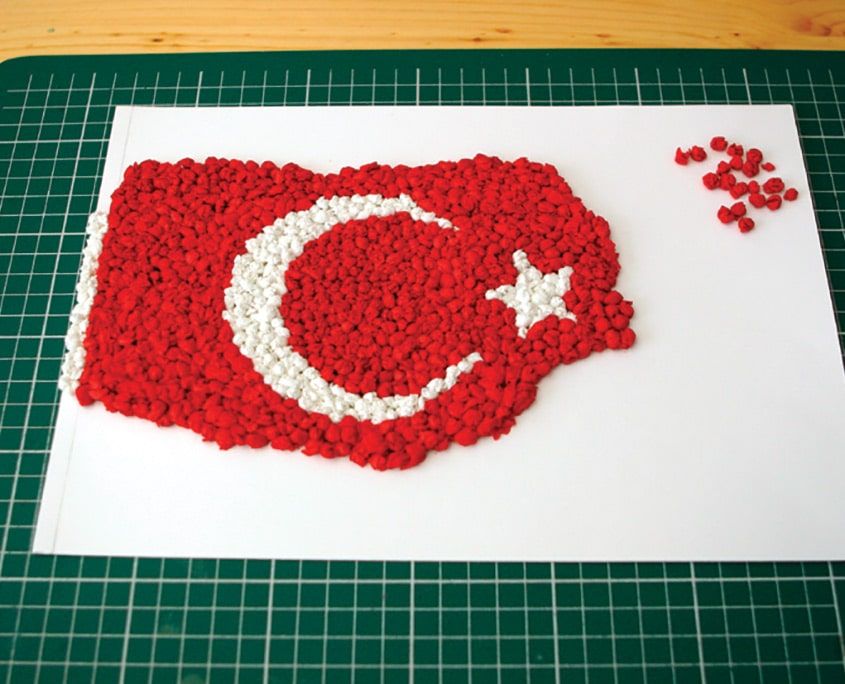 Bayrağın büyük kısmı kırmızı kağıt toplarla doldurulmuş, sağ kenarı ve birkaç top bekliyor