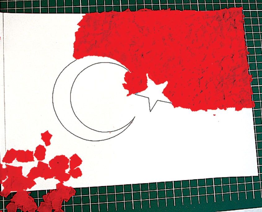 Kurşun kalemle çizilen ay yıldızın çevresine yırtılmış kırmızı kağıt parçaları yapıştırılıyor