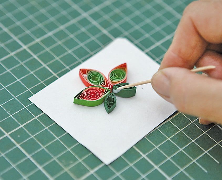 Lale motifinin altına kürdanla yeşil quilling yaprakları yapıştırılıyor, beyaz kart üzerinde