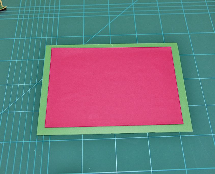 Kesim altlığında yeşil kartonun üzerine yapıştırılmış pembe dikdörtgen kart zemini