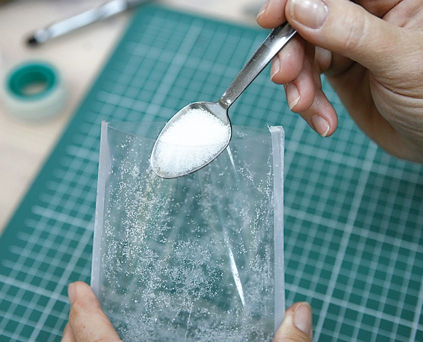 Şeffaf poşetin içine kaşıkla beyaz toz şeker doldurulması, kar görüntüsü için