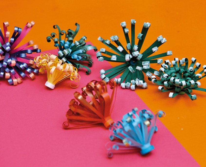 Pembe ve turuncu zemin üzerinde farklı renklerde tamamlanmış püsküllü quilling paket süsleri