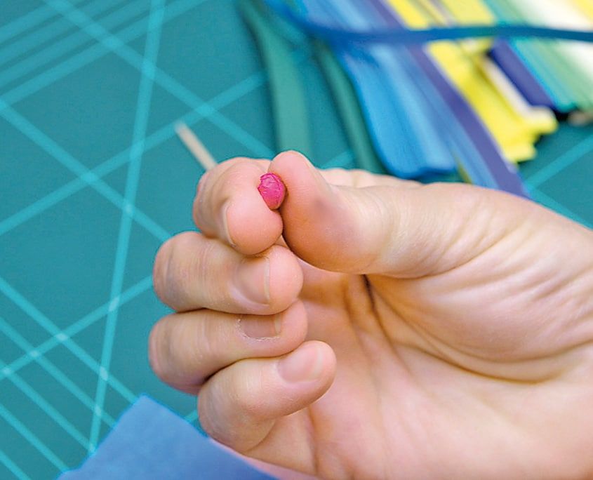 Parmak ucunda tutulan küçük pembe sıkı rulo, ağaç süsü olarak