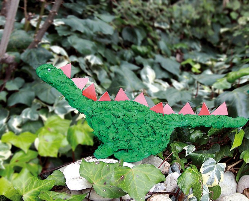 Arkadaşım dino: yeşil boyalı, sırtı pembe dikenli gazete kağıdından dinozor sarmaşık yaprakları arasında