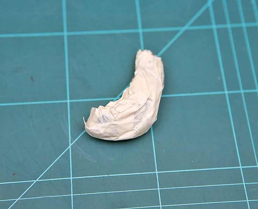 Kağıtla sarılarak şekillendirilmiş kıvrık küçük parça, dinozorun kuyruğu ya da boynu için