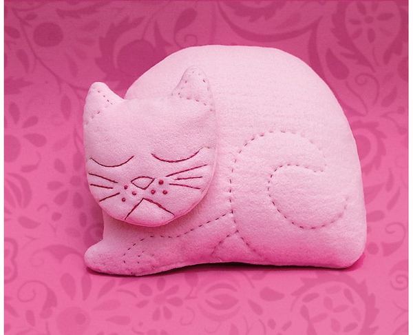 Kedi Yastığım: pembe kumaştan kıvrılıp uyuyan kedi biçimli yastık, gözleri ve bıyıkları nakışlı