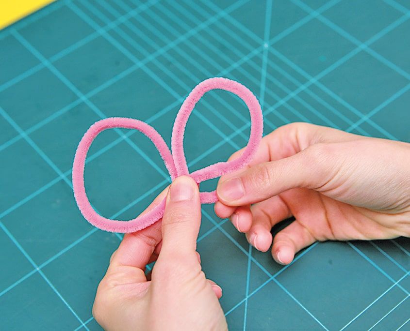 Pembe tüylü tel ortasından bükülerek iki halkalı kelebek kanadı biçimine getiriliyor