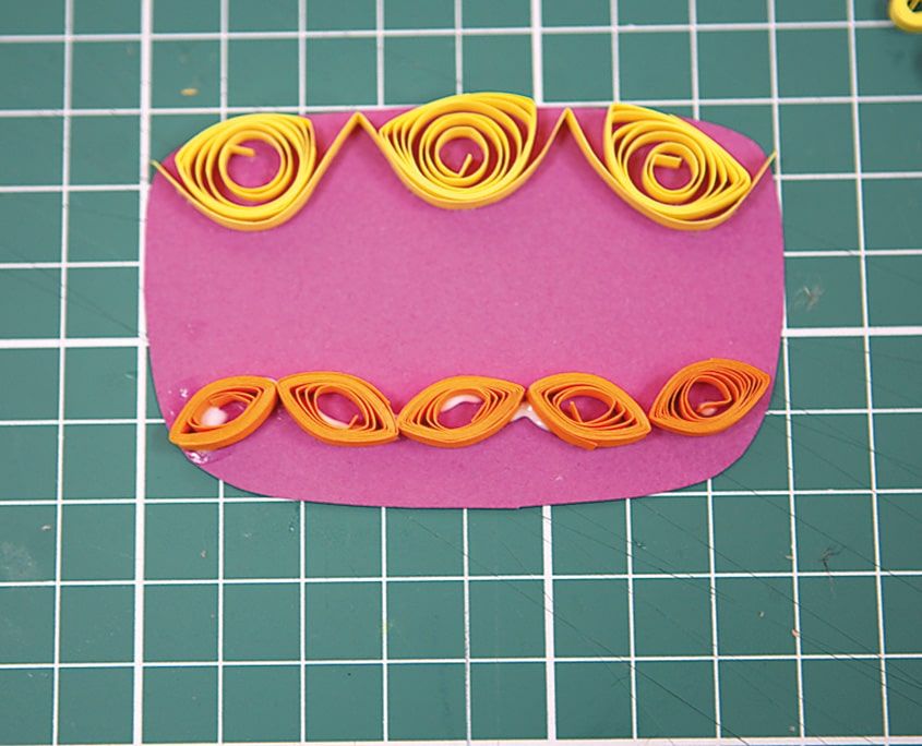 Pembe pasta katının üstüne sarı ucu açık rulolar, altına turuncu göz şekilli rulolar dizilmiş