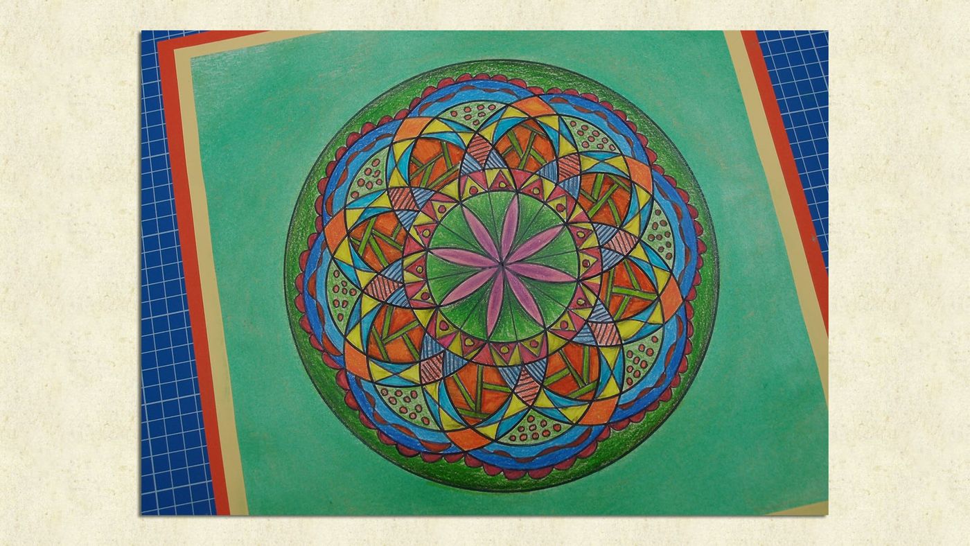 Mandala çizim ve boyama atölyesi: yeşil kağıda çizilmiş, mavi, turuncu ve pembeyle boyanmış geometrik mandala