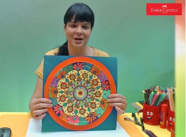 Mandala atölyesi II yayınından kare: eğitmen turuncu çerçeveli çiçekli mandalayı gösteriyor