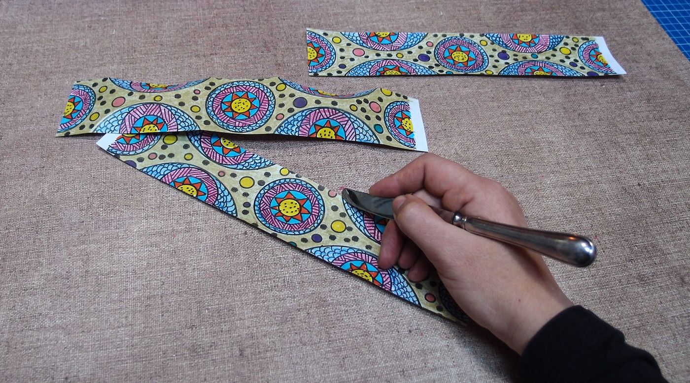 Kesilmiş desenli şeritlere bıçak sırtıyla ortadan katlama izi çiziliyor