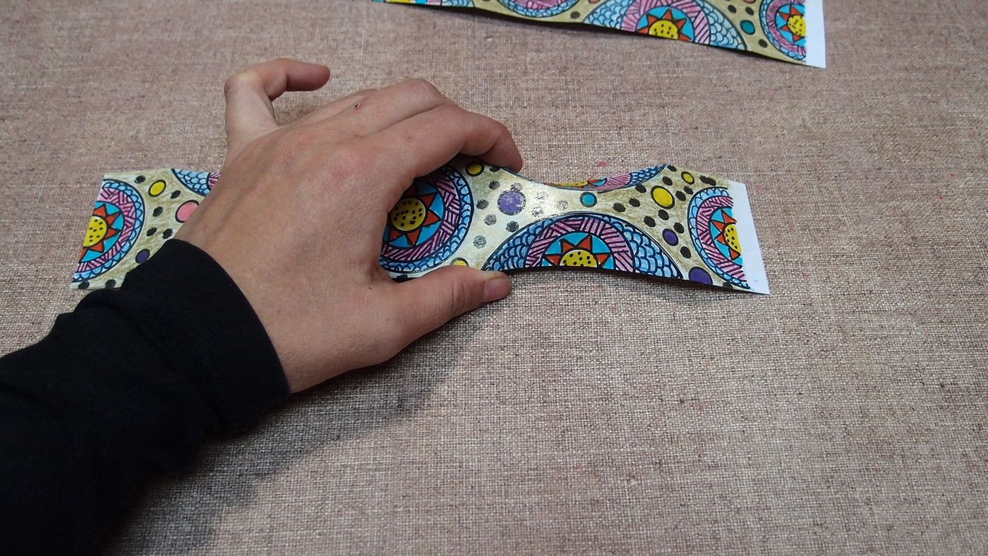Şeridin ortası parmaklarla bastırılarak iki yana kıvrılan bir forma sokuluyor