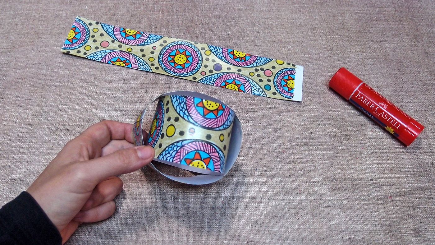 Desenli şerit halka biçiminde tutulup uçları birleştiriliyor, arkada diğer şerit ve yapıştırıcı