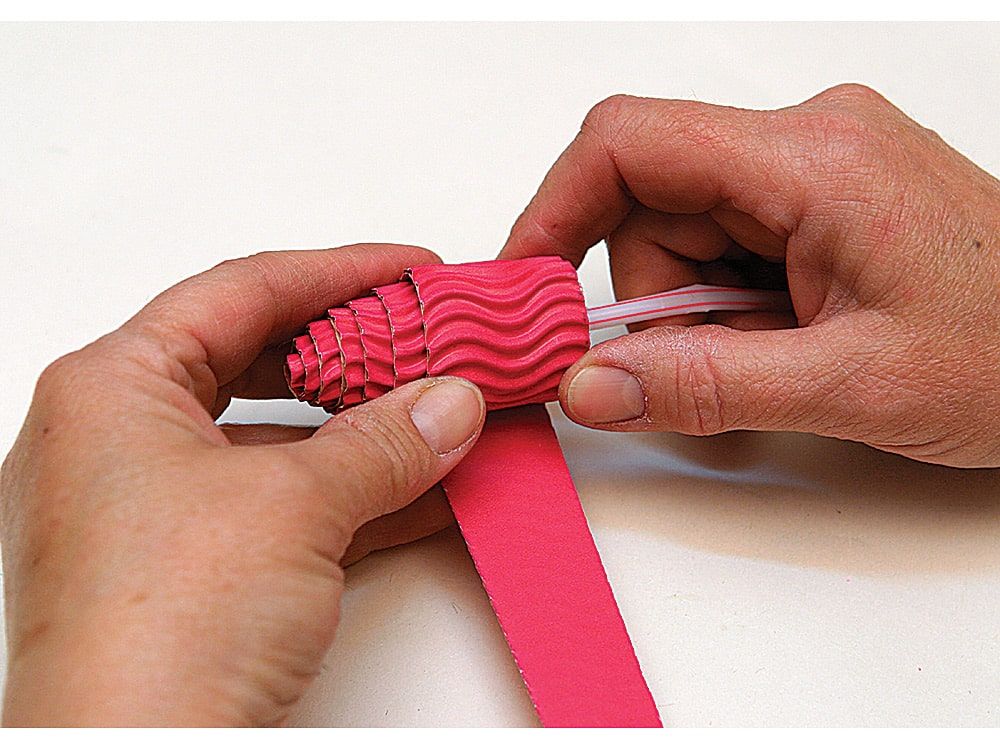 Pembe oluklu kağıt pipetin etrafına sıkıca sarılarak kukla gövdesi için tırtıklı bir rulo yapılıyor