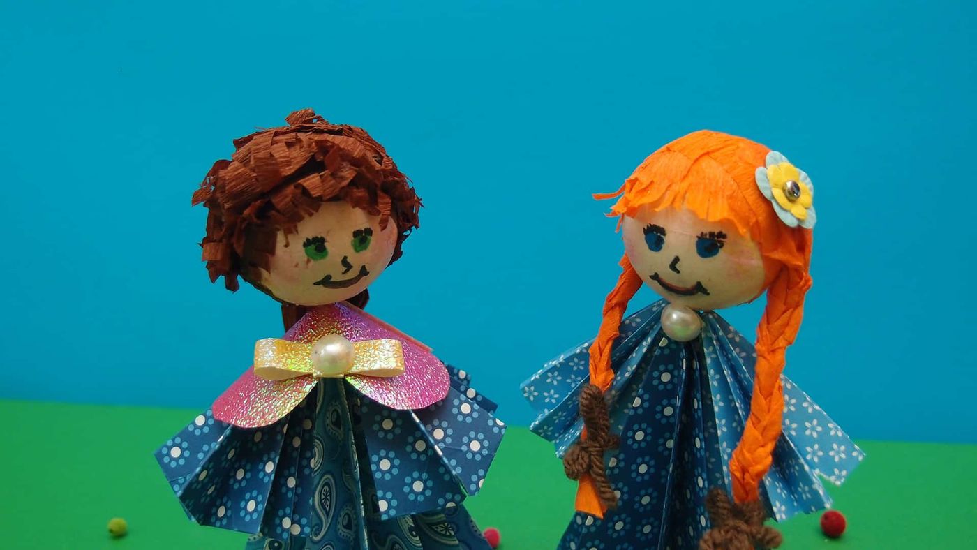 Origami bebeklerin yüzlerine yakın plan: çizilmiş gözler, gülen ağızlar ve saç dokusu