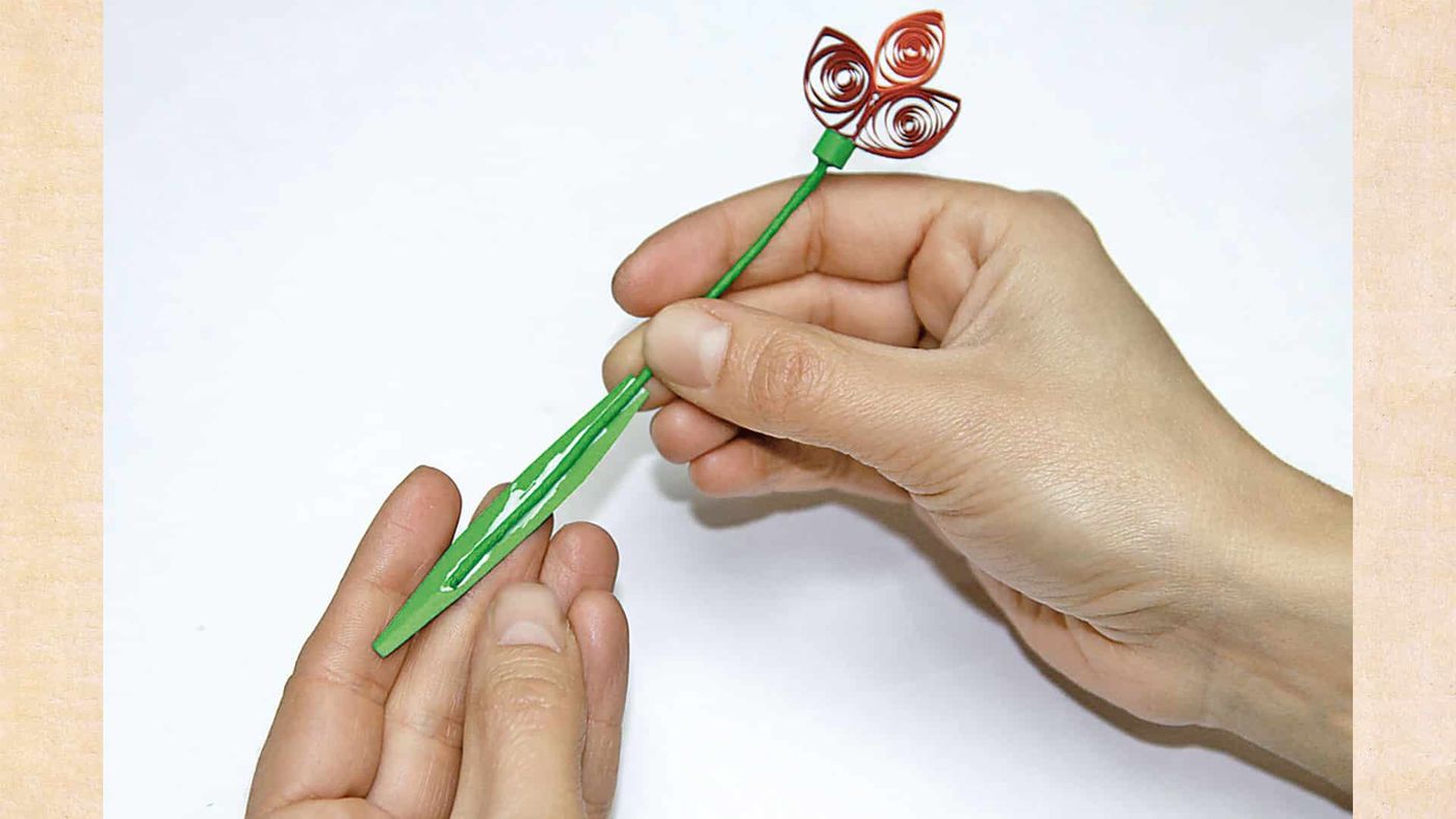 Kırmızı quilling çiçekli sapa kıvrımlı yeşil yaprağın eklenmesi