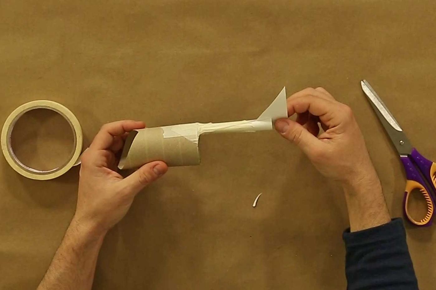 Tuvalet kağıdı rulosuna kartondan kuyruk takılması, yanında koli bandı ve makas