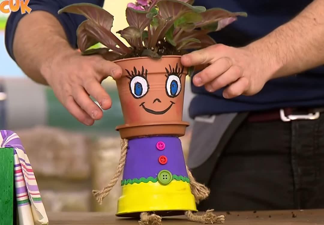 Sevimli saksı: üst üste konmuş iki toprak saksıdan yüzlü figür, başında yapraklı bitki, ip kolları ve bacakları