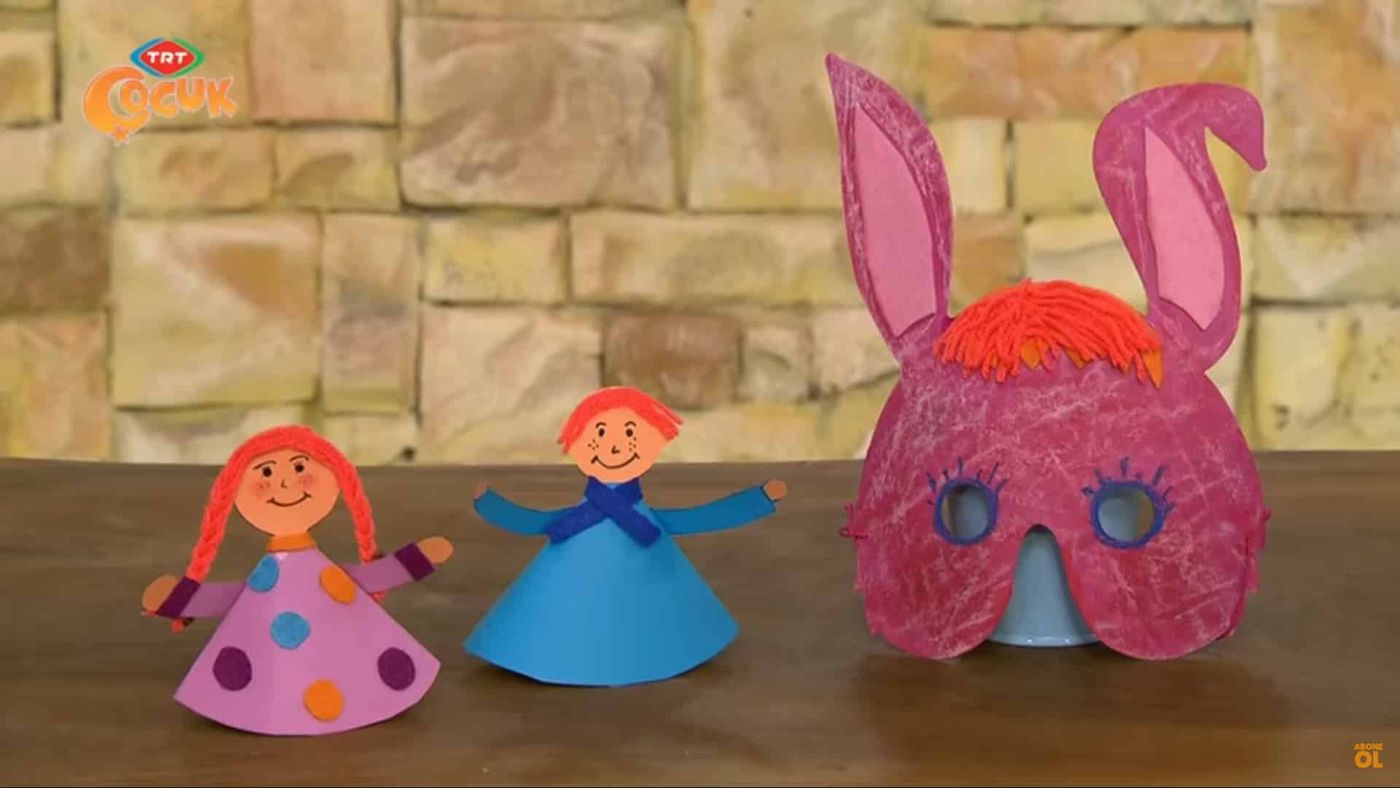 Karton Kardeşler: puantiyeli pembe ve mavi koni kartondan iki bebek ile turuncu yün saçlı pembe tavşan maskesi