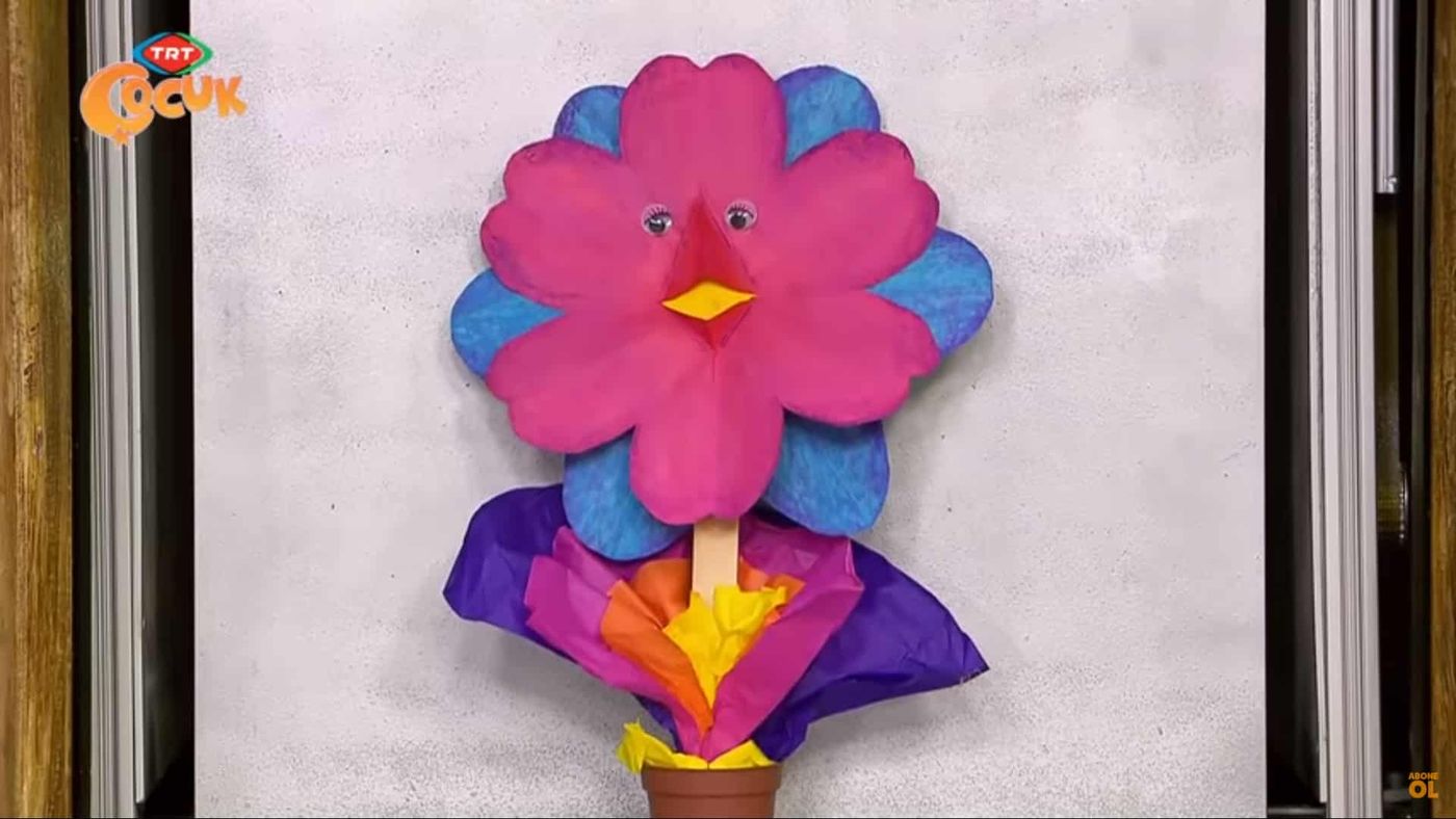 Pembe taç yapraklı, mavi kenarlı kağıt çiçek ile mor ve sarı kağıt yapraklı saksı süsü